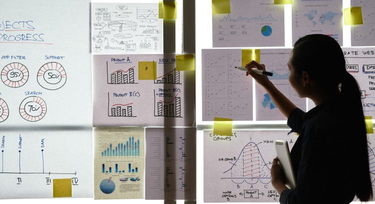 Business woman analyzing charts and graphs handing on the wall