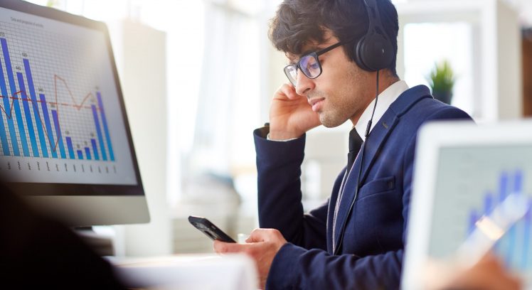 Businessman with smartphone and headphones listening to online program record for financiers