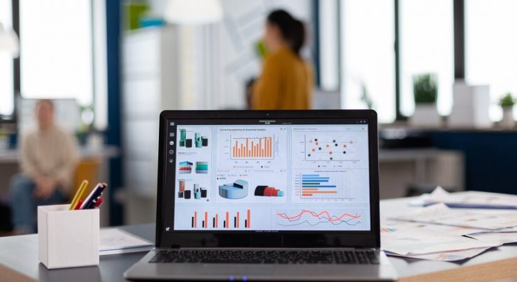 close-up-laptop-start-up-company-office-with-charts-statistics-workplace-area-business-center-with-multi-ethnic-employees-it-shot-room-with-modern-furniture-blue-wall_482257-7323