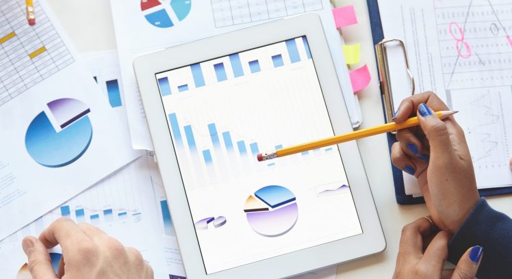 Cropped shot of hands of University student and teacher checking homework, dark-skinned girl, pointing at tablet pc with diagrams using yellow pencil, man analyzing graphs, correcting mistakes